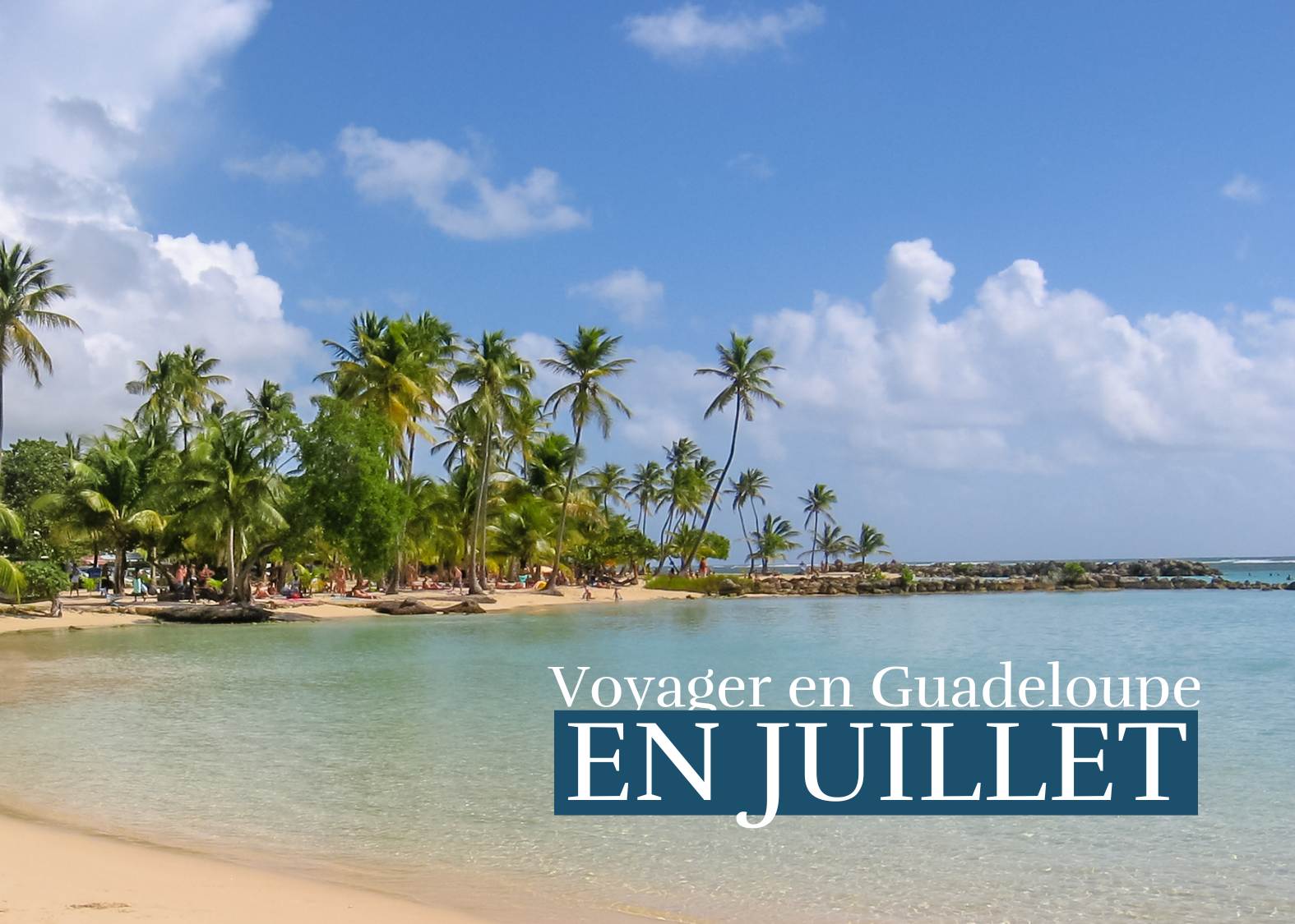 Plage de sable blanc en Guadeloupe en juillet avec mer turquoise et palmiers sous le soleil tropical